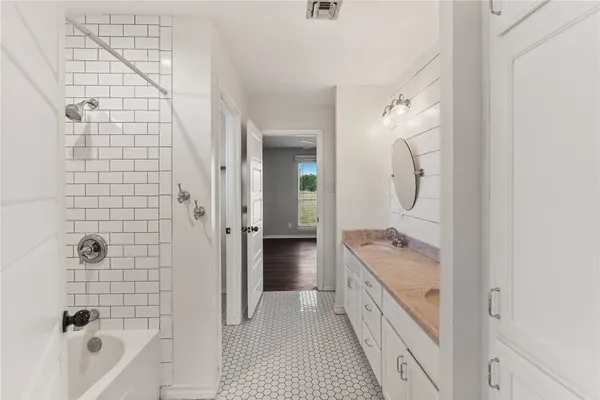 a bathroom with a granite countertop sink a mirror a bathtub and shower