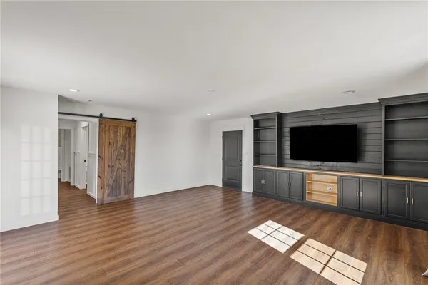 a living room with stainless steel appliances furniture and wooden floor
