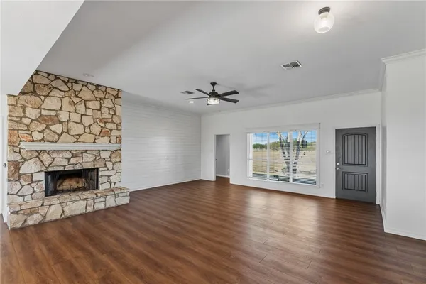 a view of an empty room with wooden floor fireplace and a window