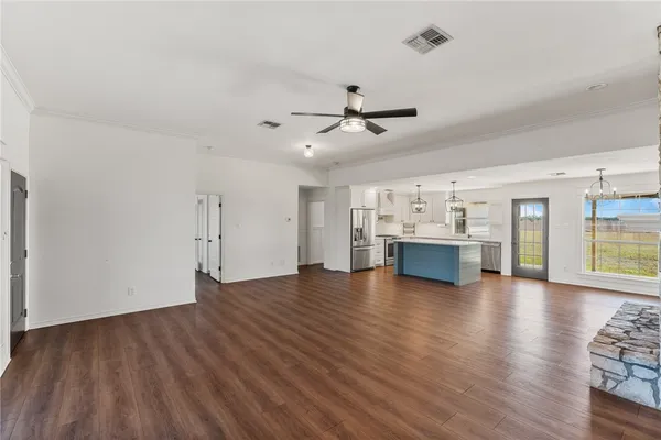 a view of a kitchen and an empty room with wooden floor and windows