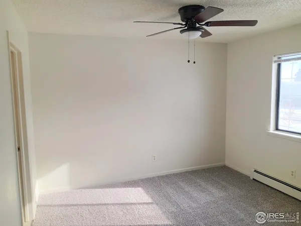 an empty room with a window and a fan
