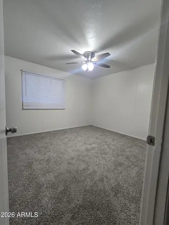 an empty room with a chandelier fan and windows