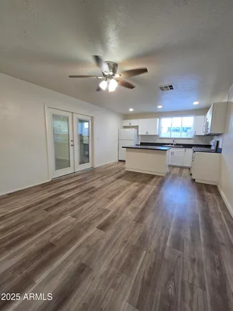 a large kitchen with a sink dishwasher a stove and white countertops with wooden floor