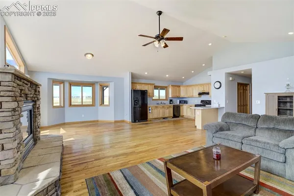 a living room with couches and kitchen view with wooden floor