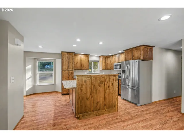 a kitchen with stainless steel appliances kitchen island granite countertop a refrigerator and a sink