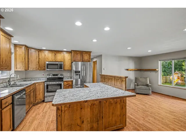 a kitchen with stainless steel appliances granite countertop a sink dishwasher stove and refrigerator