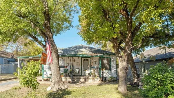 a front view of a house with a yard fountain and a tree