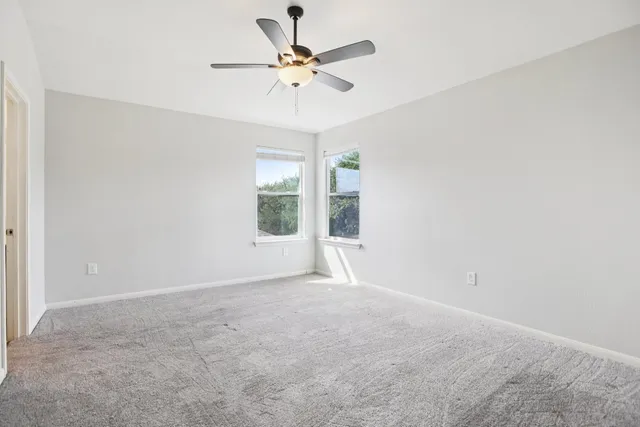 an empty room with a window and a fan