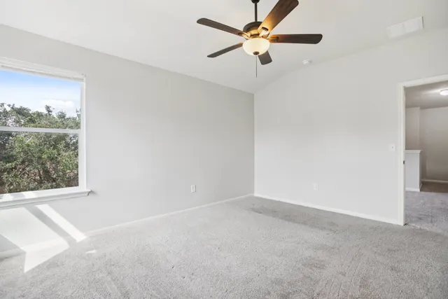 an empty room with a window and a fan