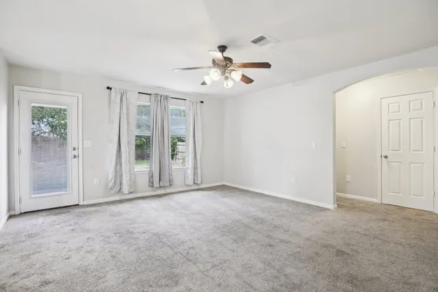 an empty room with windows and fan