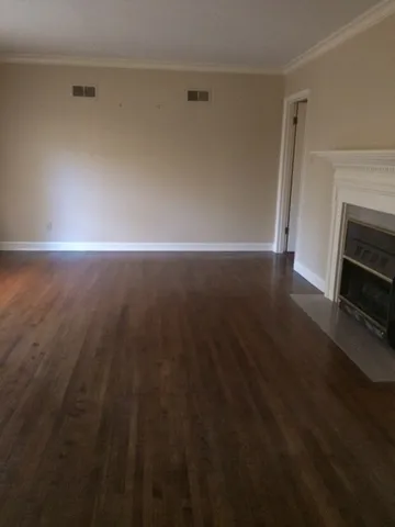 a view of empty room with wooden floor and fireplace