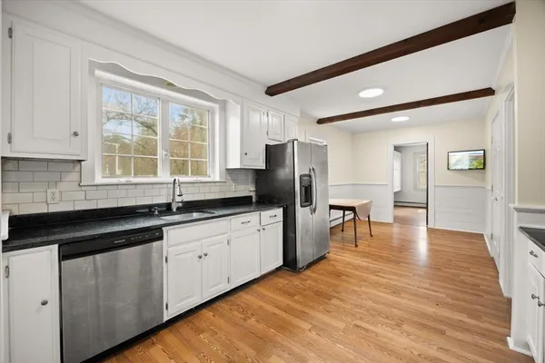 a kitchen with stainless steel appliances granite countertop a refrigerator a sink dishwasher a stove and white countertops with wooden floor