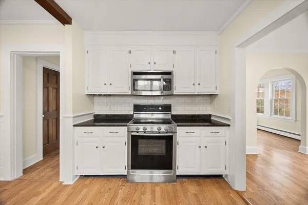 a kitchen with stainless steel appliances granite countertop a stove and a white cabinets