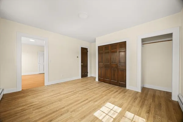 a view of an empty room with wooden floor and closet
