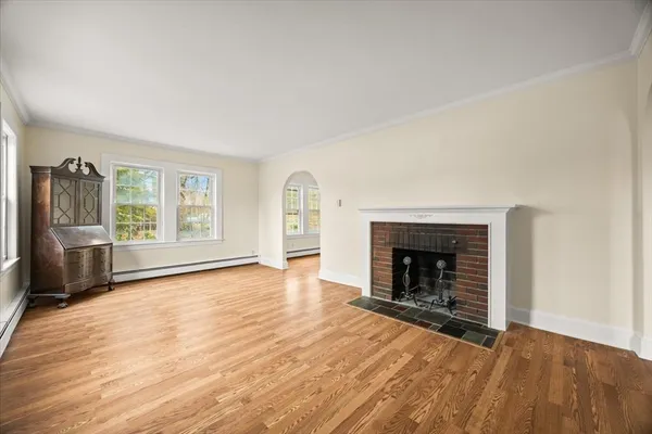 an empty room with windows fireplace and wooden floor