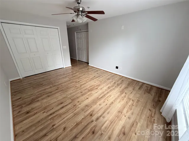 a view of a room with wooden floor and ceiling fan