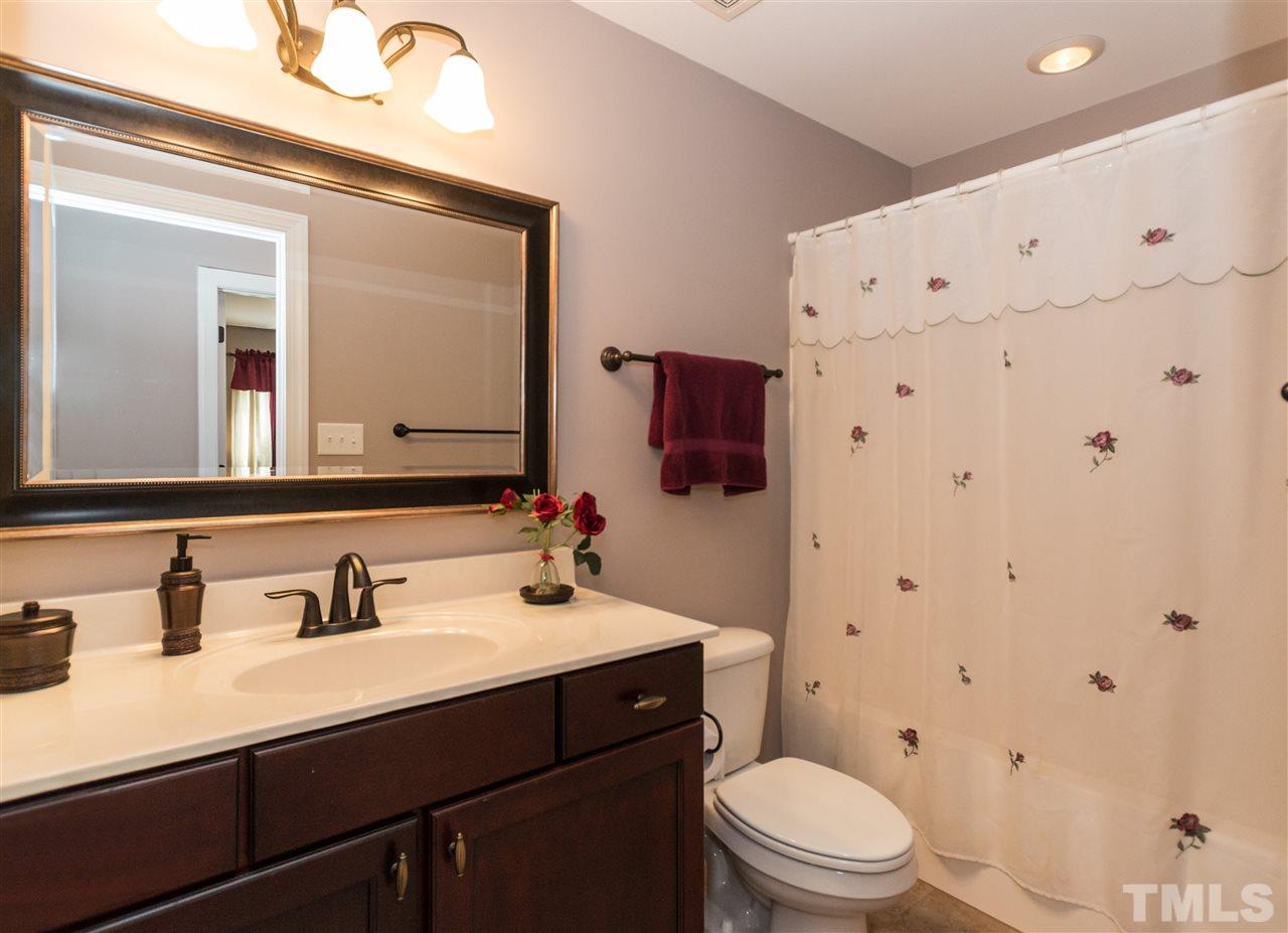 4805 Stoneyoak Lane Raleigh, NC 27610 - Photo 18 of 25 a bathroom with a sink a toilet a mirror and shower curtain