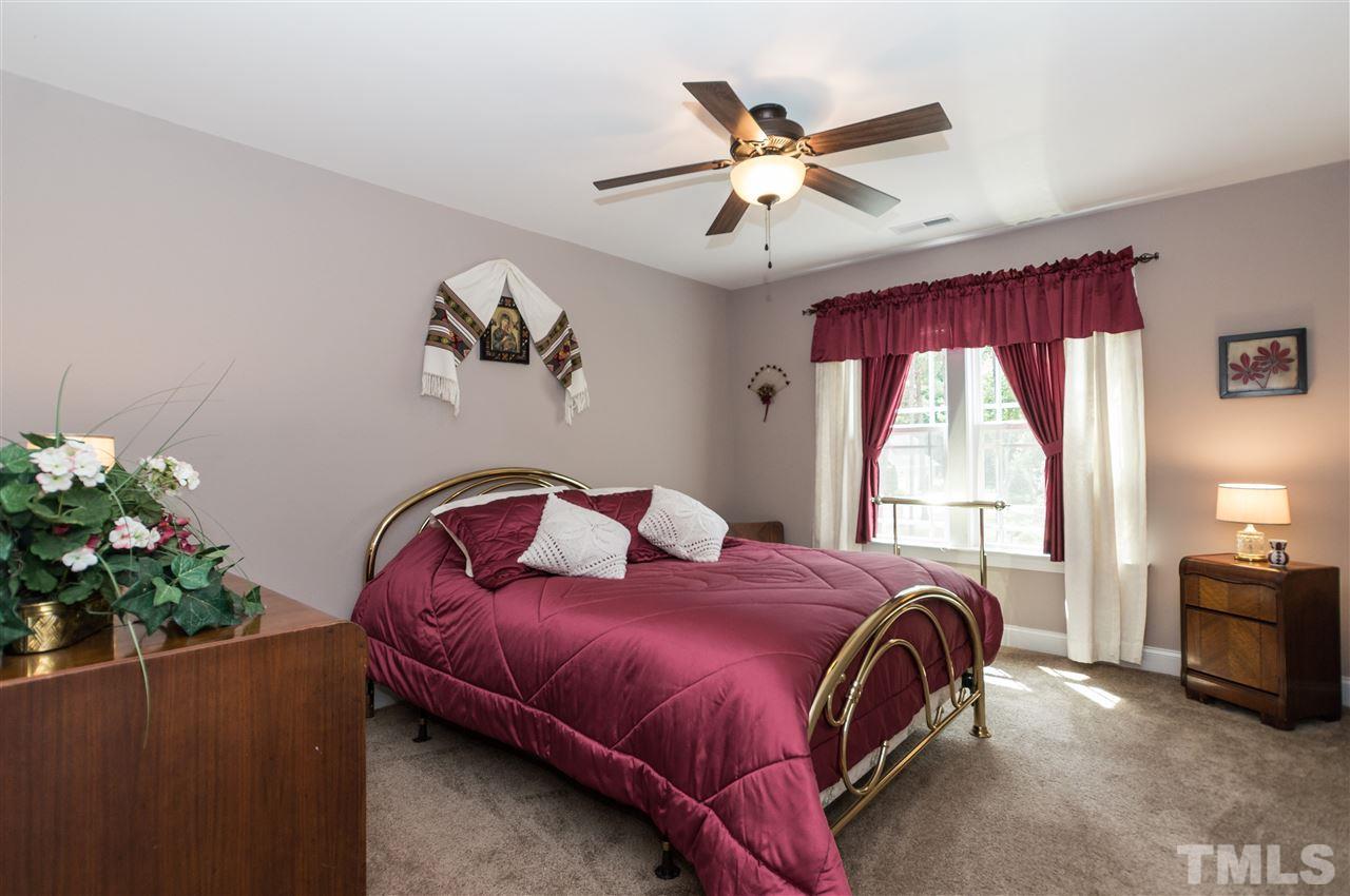 4805 Stoneyoak Lane Raleigh, NC 27610 - Photo 19 of 25 a bedroom with a bed chandelier and a window
