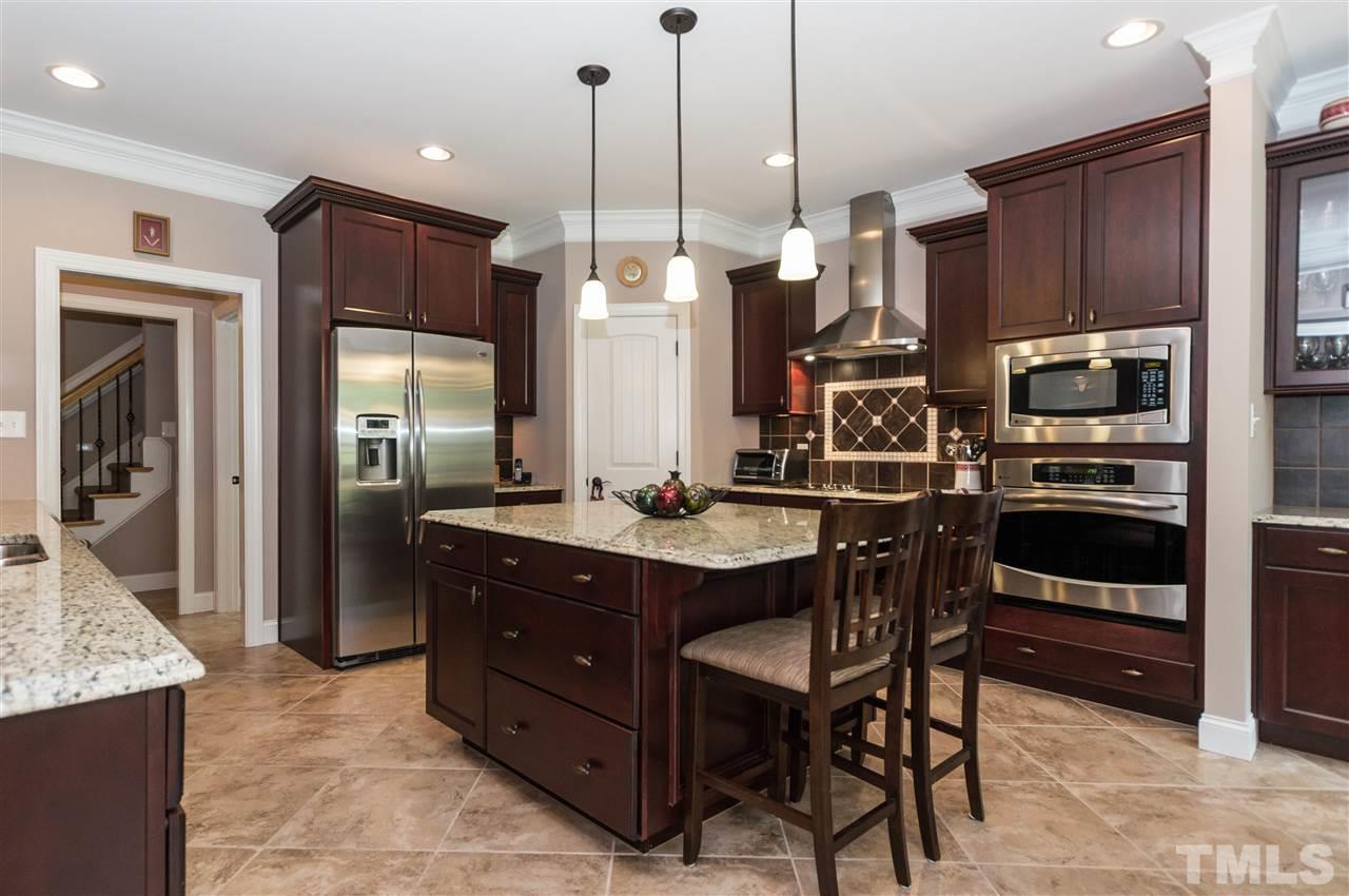 4805 Stoneyoak Lane Raleigh, NC 27610 - Photo 7 of 25 a kitchen with stainless steel appliances a stove a refrigerator a sink a oven with a dining table and chairs