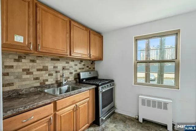 an empty room with wooden floor cabinet and windows