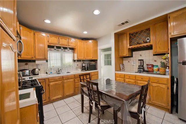 a kitchen with stainless steel appliances kitchen island granite countertop a table chairs sink and cabinets