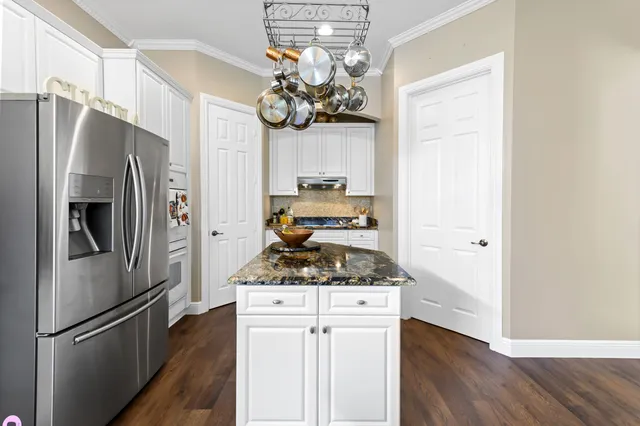 a kitchen with stainless steel appliances granite countertop a refrigerator a stove a sink and dishwasher with wooden floor