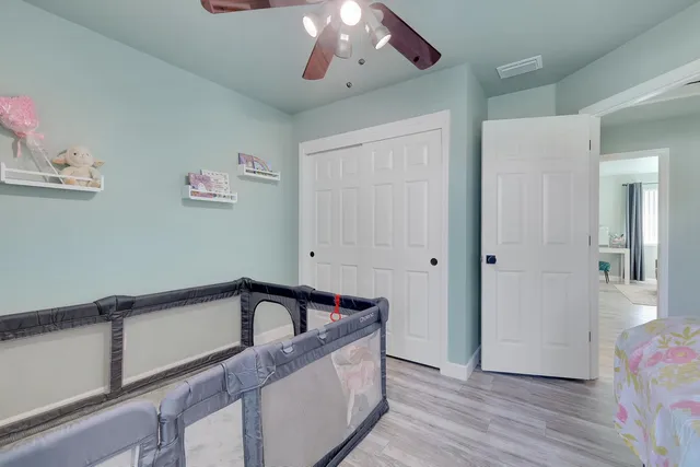 a view of a hallway to a room with wooden floor and chandelier
