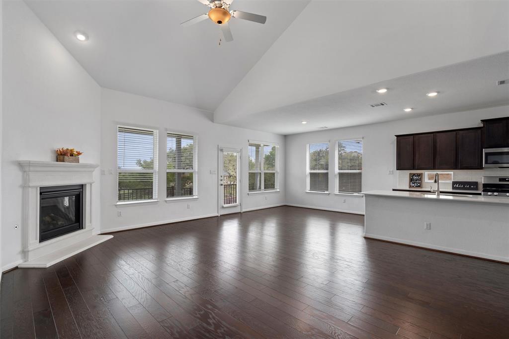236 Prato Place Georgetown, TX 78628 - Photo 11 of 40 Hardwood floors stretch across this open living area, crowned by a vaulted ceiling and a stately fireplace.