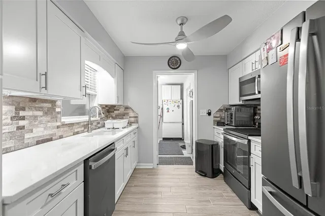 a kitchen with a sink stainless steel appliances cabinets and a window