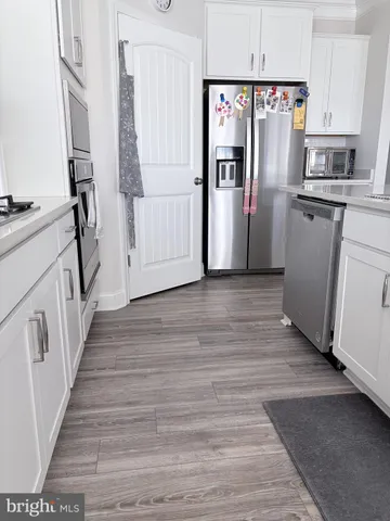 a view of a kitchen with wooden floor and electronic appliances