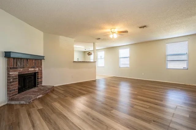 an empty room with wooden floor fireplace and windows