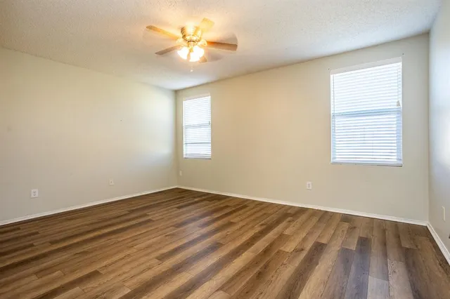 a view of an empty room with a window and wooden floor