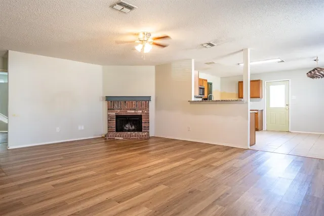 a view of empty room with wooden floor and fireplace