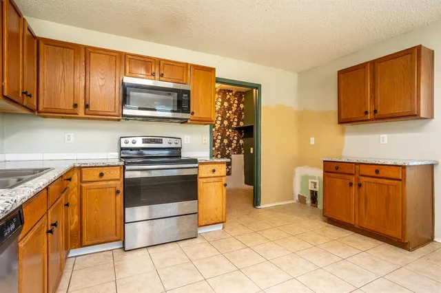 a kitchen with stainless steel appliances granite countertop a stove a sink and a microwave