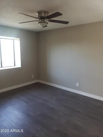 an empty room with wooden floor fan and windows