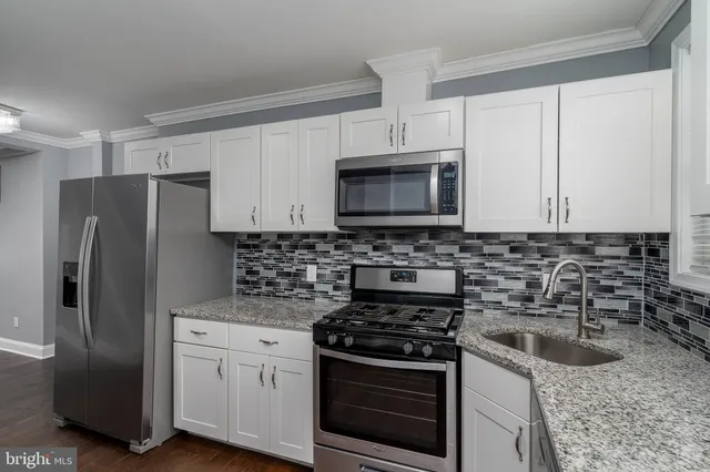 a kitchen with granite countertop a sink stove and refrigerator