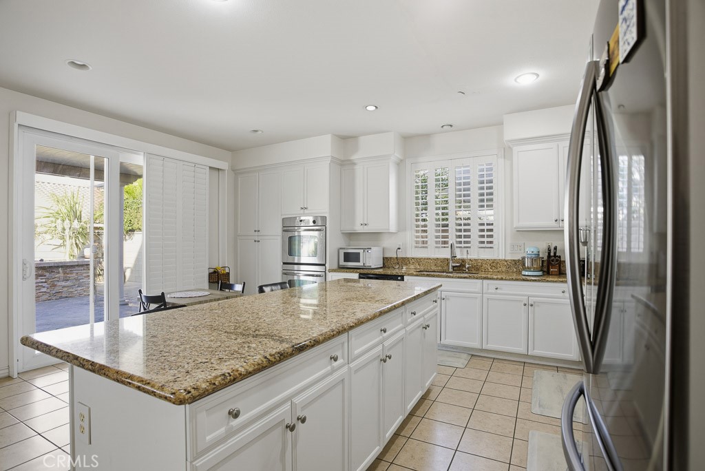 6865 Hop Clover Road Eastvale, CA 92880 - Photo 19 of 59 a kitchen with granite countertop a sink stove and refrigerator