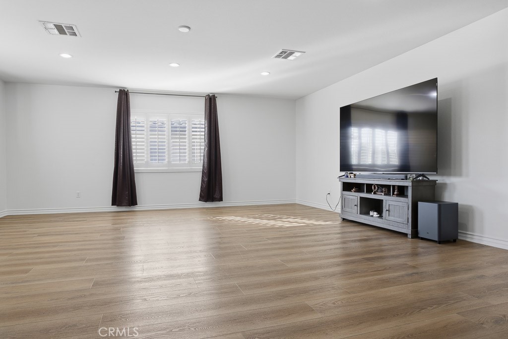 6865 Hop Clover Road Eastvale, CA 92880 - Photo 26 of 59 a view of empty room with wooden floor and kitchen view