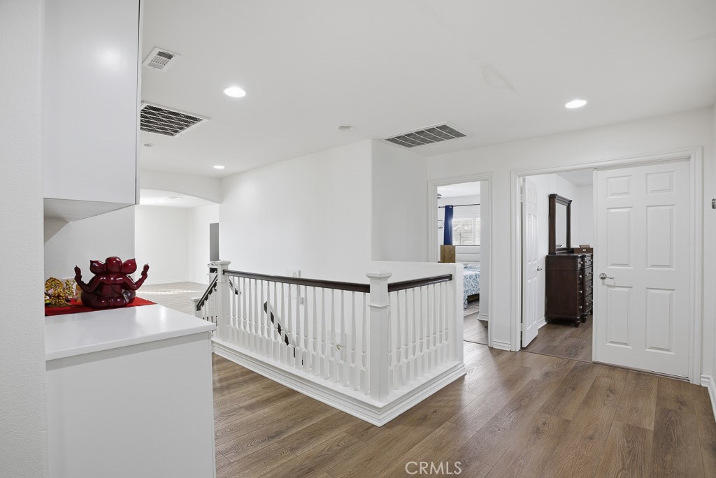 6865 Hop Clover Road Eastvale, CA 92880 - Photo 32 of 59 a view of a hallway with a white stove a refrigerator and wooden floor