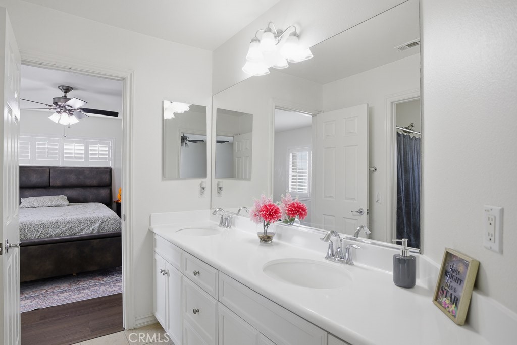 6865 Hop Clover Road Eastvale, CA 92880 - Photo 37 of 59 a en suite bathroom with a granite countertop double vanity sink and a mirror