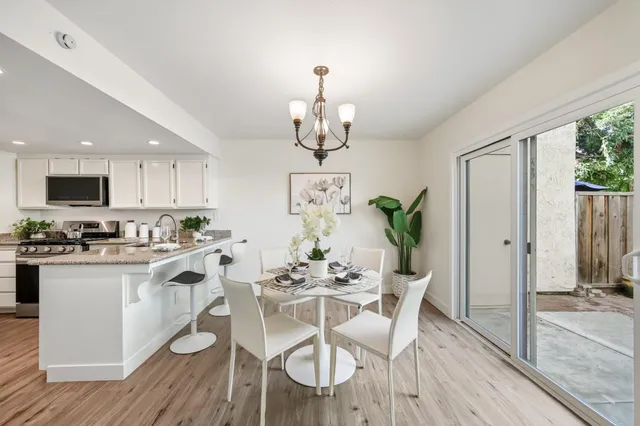 a dining room with wooden floor a chandelier a wooden table and chairs
