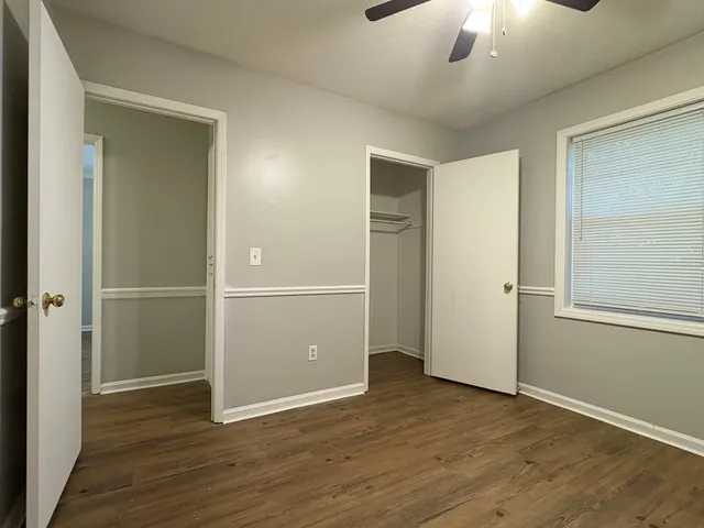 an empty room with wooden floor closet and windows