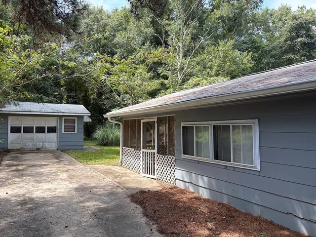 a view of a house with a yard and large tree