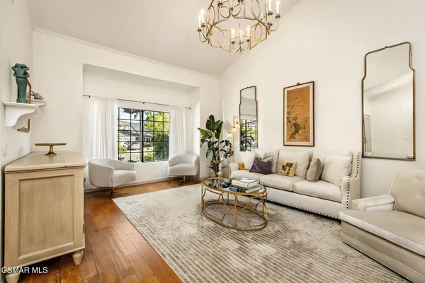 a living room with furniture a chandelier and a wooden floor