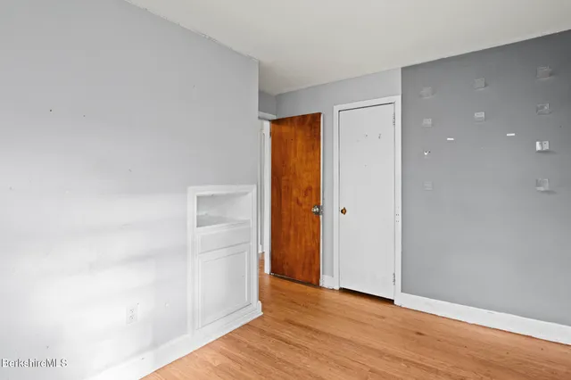 a view of an empty room with wooden floor and closet