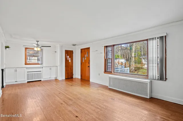 a view of an empty room with a window and wooden floor