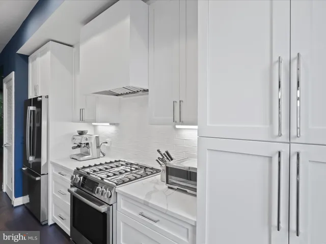 a kitchen with stainless steel appliances granite countertop white cabinets and a stove