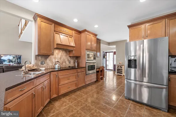 a kitchen with stainless steel appliances granite countertop a refrigerator a sink dishwasher a stove top oven a refrigerator and cabinets