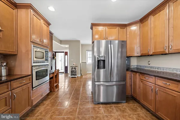 a kitchen with stainless steel appliances granite countertop a refrigerator a stove and a sink