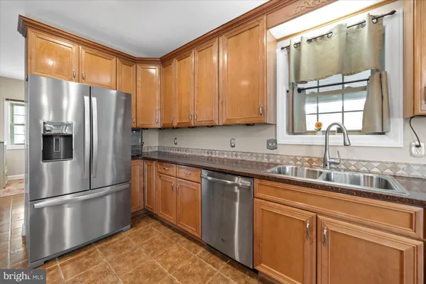 a kitchen with stainless steel appliances granite countertop a refrigerator a sink and white cabinets